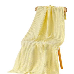 Yellow waffle bath towel draped on a wooden stand