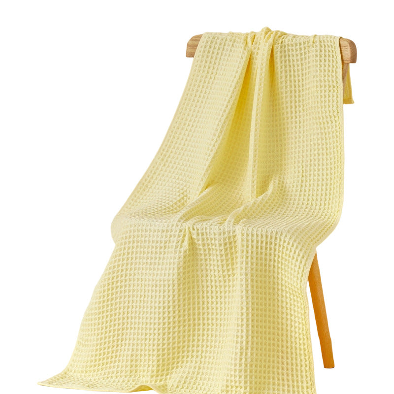 Yellow waffle bath towel draped on a wooden stand