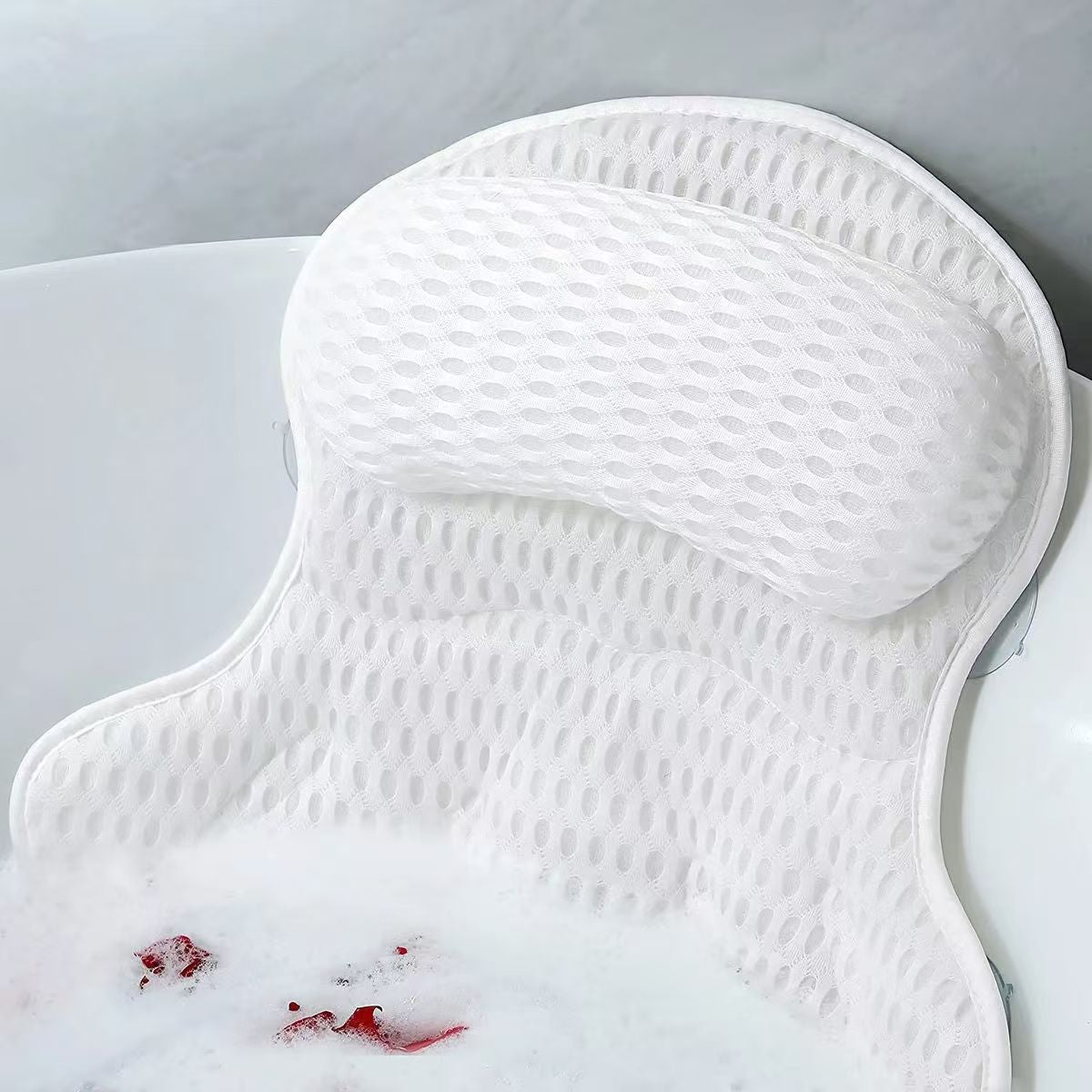 White mesh bath pillow resting against a bathtub