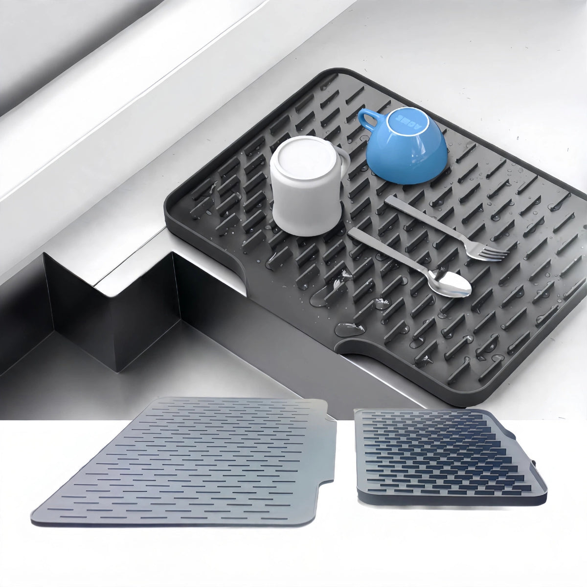 Grey silicone dish drying mat beside a sink with cups and cutlery